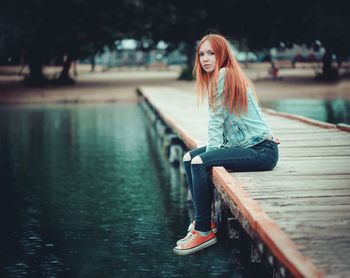 Portrait of woman sitting on pier over lake