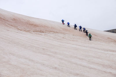 Hikers climbing sand dunes in desert