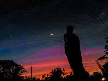 Low angle view of silhouette man standing against sky at sunset