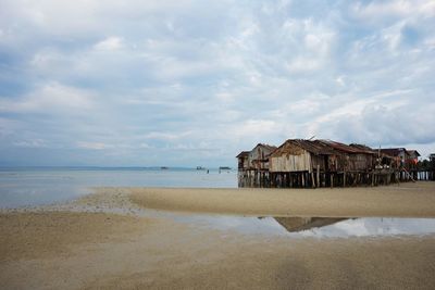 View of calm beach against cloudy sky