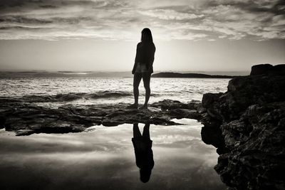 Silhouette woman standing on beach against sky during sunset