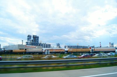 Cars on road against cloudy sky