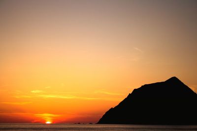 Scenic view of sea and silhouette mountain against sky during sunset