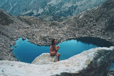 Naked woman on a rock at 2900 meters high with a lake in the background