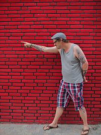 Full length of man standing against red brick wall