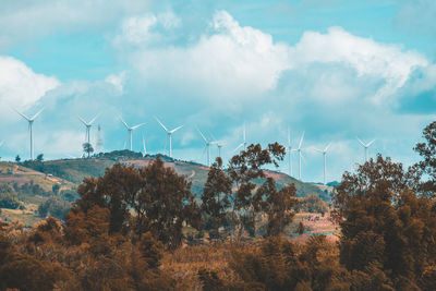 Panoramic view of wind turbines on land against sky