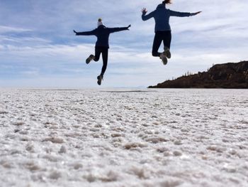 Low angle view of men jumping against sky