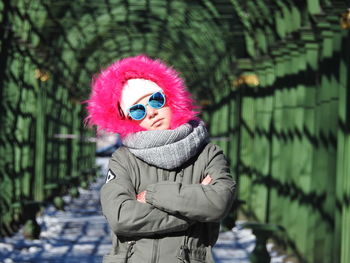 Portrait of girl in warm clothing with arms crossed standing at park