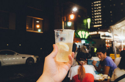 Close-up of people holding drink in city at night