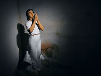 Portrait of woman standing against white wall