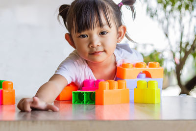 Portrait of cute girl with toy blocks on table