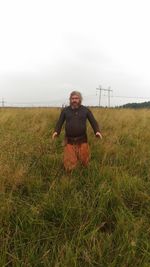 Portrait of man standing on field against sky