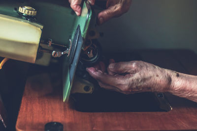 Cropped hands of tailor using sewing machine while working in workshop
