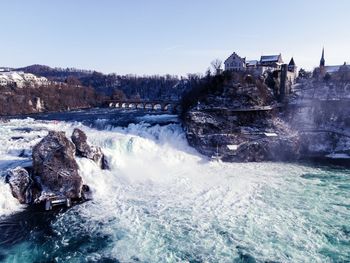 Water splashing on rocks against clear sky