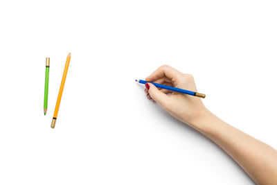 Close-up of hand holding pencils against white background