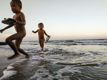 Full length of shirtless boy on beach against sky