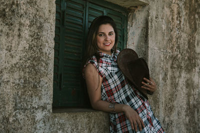 Portrait of woman standing by window of built structure