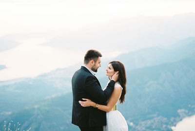 Side view of couple standing against mountain