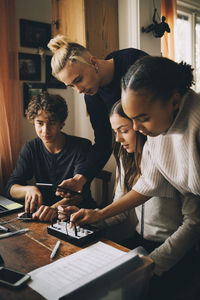 Teenage friends using audio equipment while doing homework at home