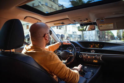 Bald bearded middle-aged man drives a car