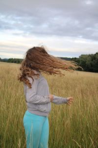 Woman with arms raised on field against sky