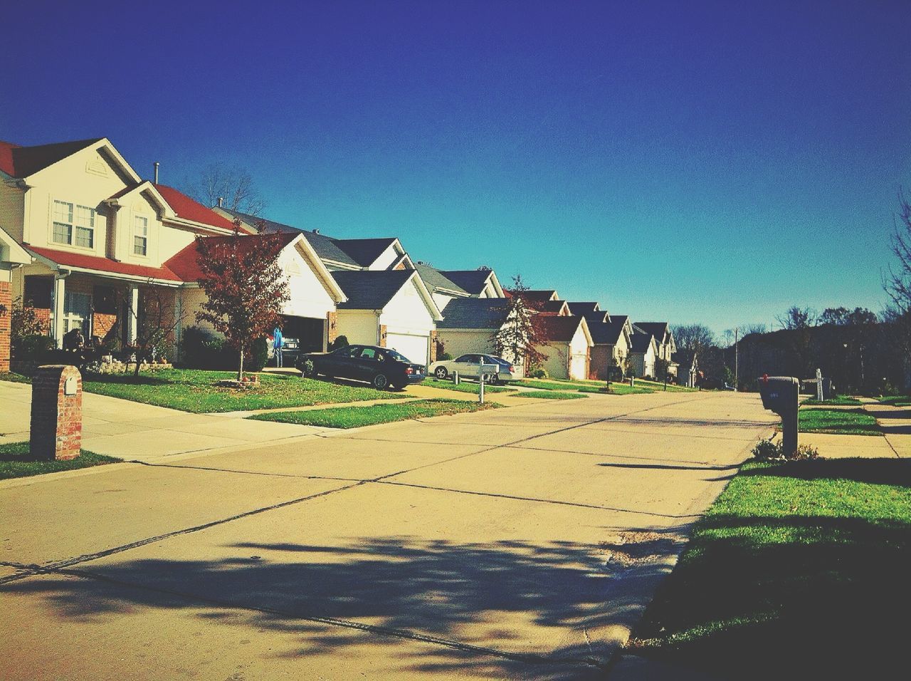 building exterior, architecture, built structure, clear sky, blue, house, copy space, sunlight, shadow, grass, residential structure, sky, outdoors, residential building, day, street, no people, footpath, sunny, incidental people