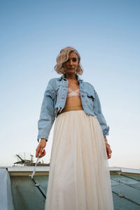 Low angle view of woman standing against clear sky