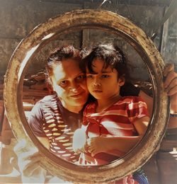 Portrait of smiling mother with cute daughter seen through circular equipment