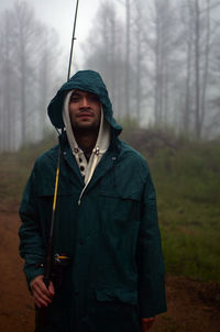 Young man standing in forest with a fish can