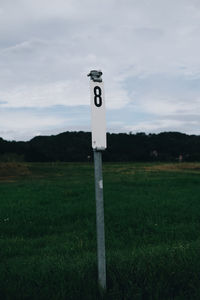 Information sign on grassy field against sky