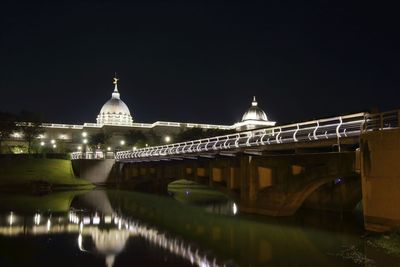 Illuminated bridge over river at night