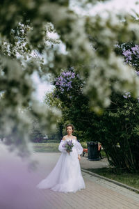 Woman holding flower bouquet against plants