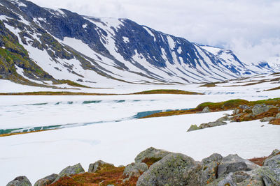 Melting snow starts to reveal a mountain lake high up on strynfjell mountain in norway
