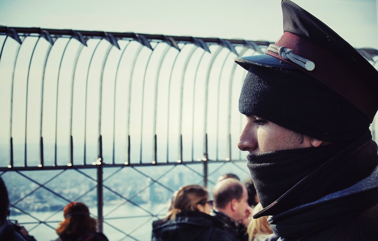 lifestyles, men, leisure activity, standing, casual clothing, rear view, togetherness, protection, person, sky, railing, day, fence, warm clothing, safety, focus on foreground, three quarter length