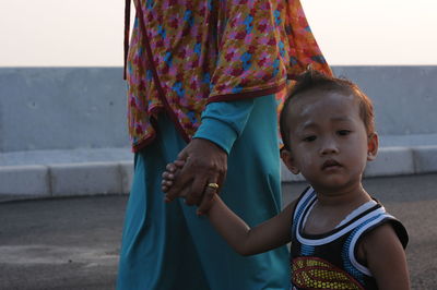 Portrait of mother with daughter standing against wall