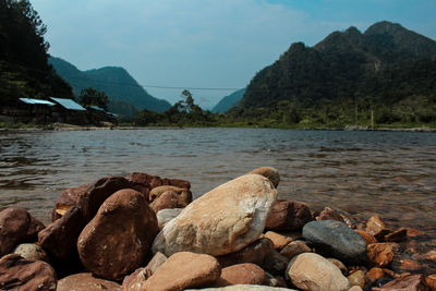 Rocks by lake against sky