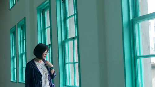 Side view of young woman looking through window