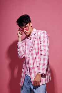 Young man standing against yellow background