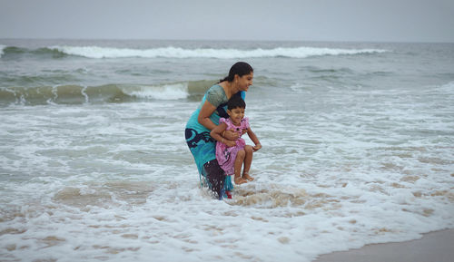 Mother and daughter playing on sea shore