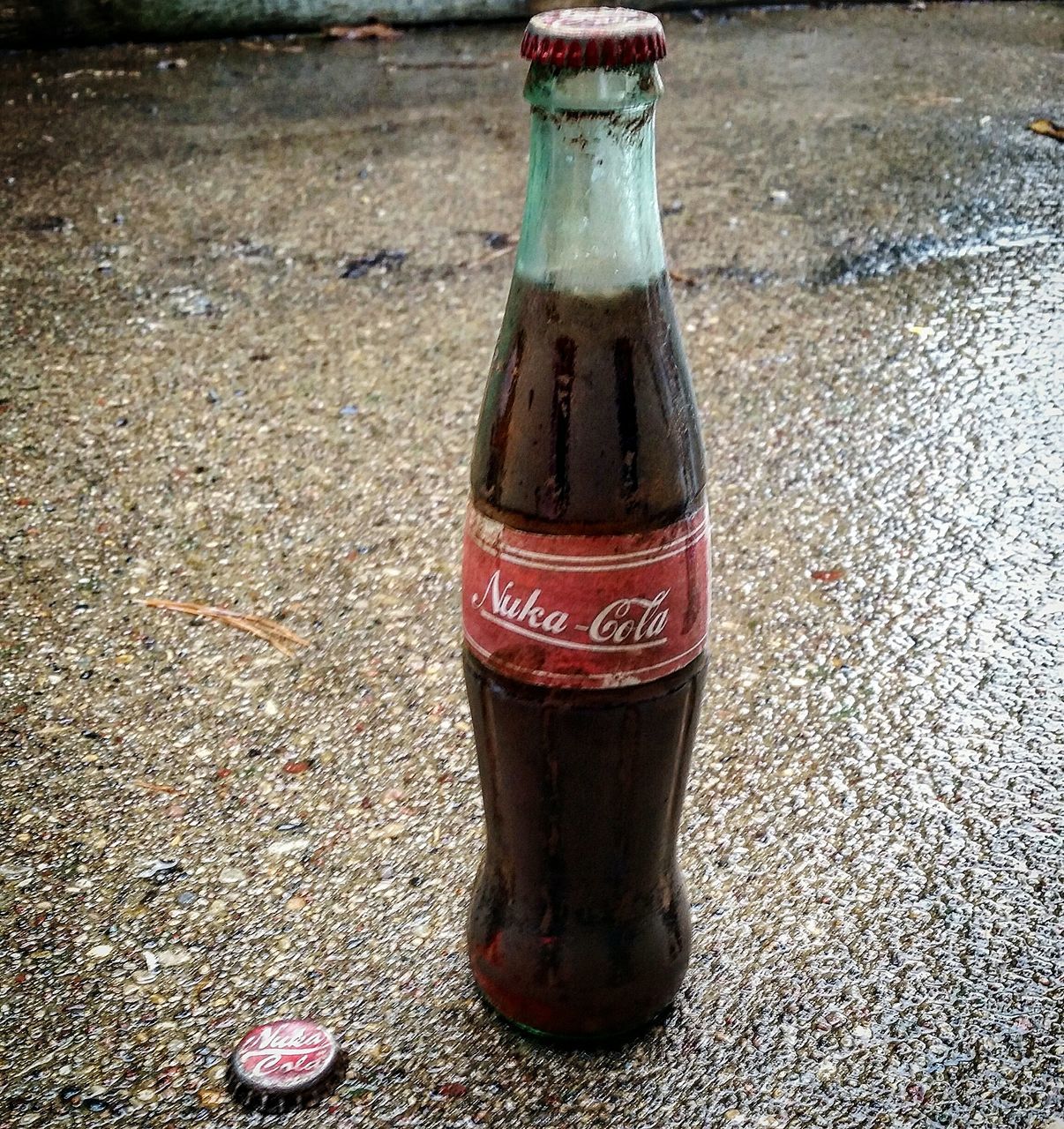 close-up, red, still life, metal, street, text, drink, outdoors, no people, day, bottle, single object, high angle view, western script, communication, rusty, container, metallic, focus on foreground, sunlight