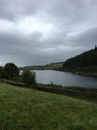 Calm countryside lake against cloudy sky