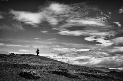 Mid distant man walking on mountain against sky