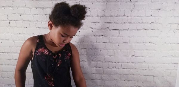 Young woman looking away against wall