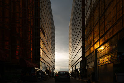 Car driving in between two office buildings during the sunset