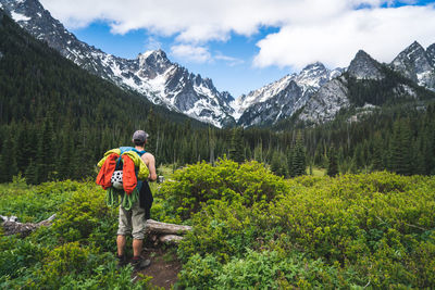 Rear view of man on snowcapped mountain against sky