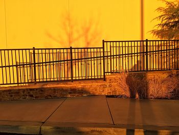 Yellow railing against sky during sunset