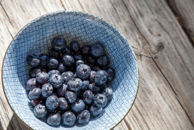 Organic blueberries in a blue and white bowl on the rustic wood background of an old farm table