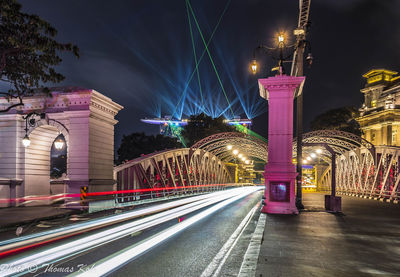 Light trails on bridge against sky at night