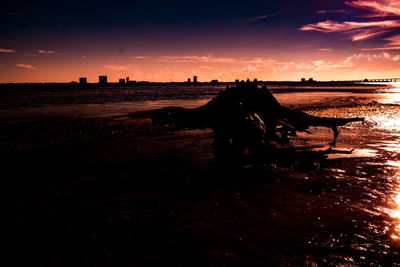 Silhouette people on beach against sky during sunset