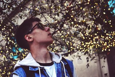 Close-up of boy standing against tree